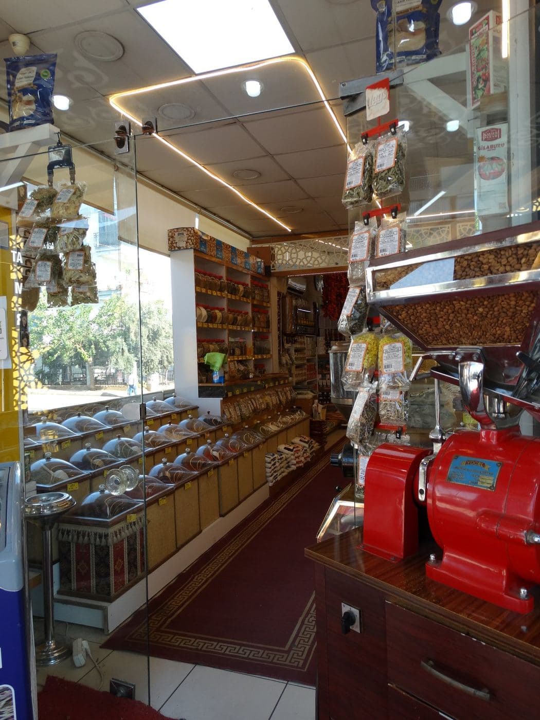 The Öz Kervan counter: a red antique coffee grinder, a kilim and full shelves behind it