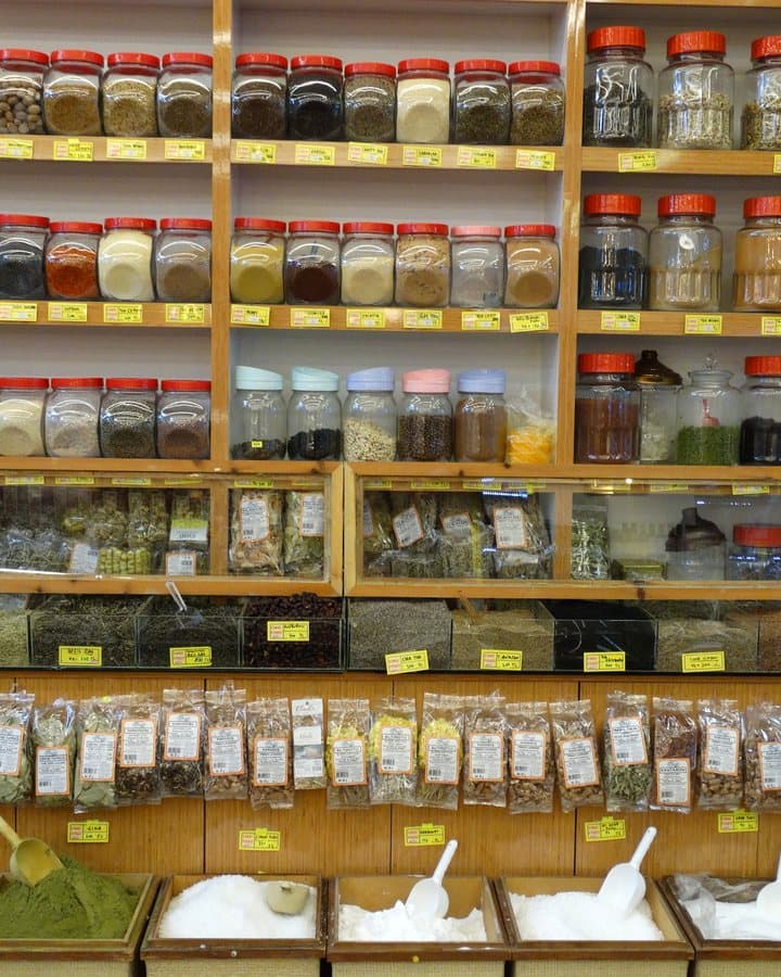 Rows of spice jars on the shelf, loose tea and medicinal herb bins below